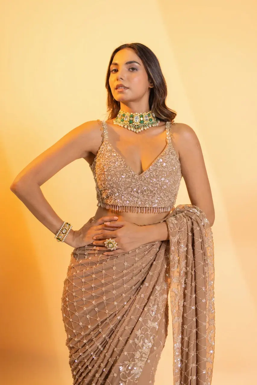 A captivating champagne georgette saree adorned with intricate hand embroidery, featuring exquisite