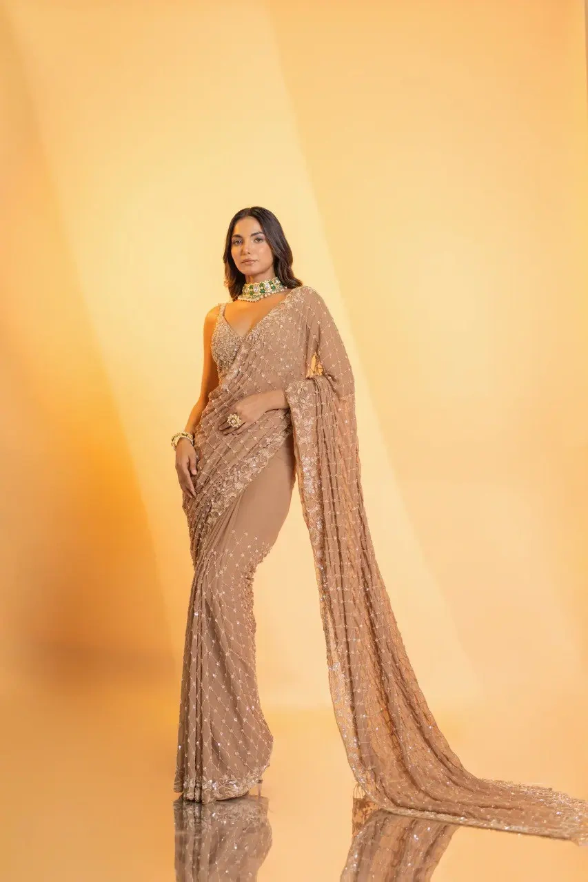 A captivating champagne georgette saree adorned with intricate hand embroidery, featuring exquisite