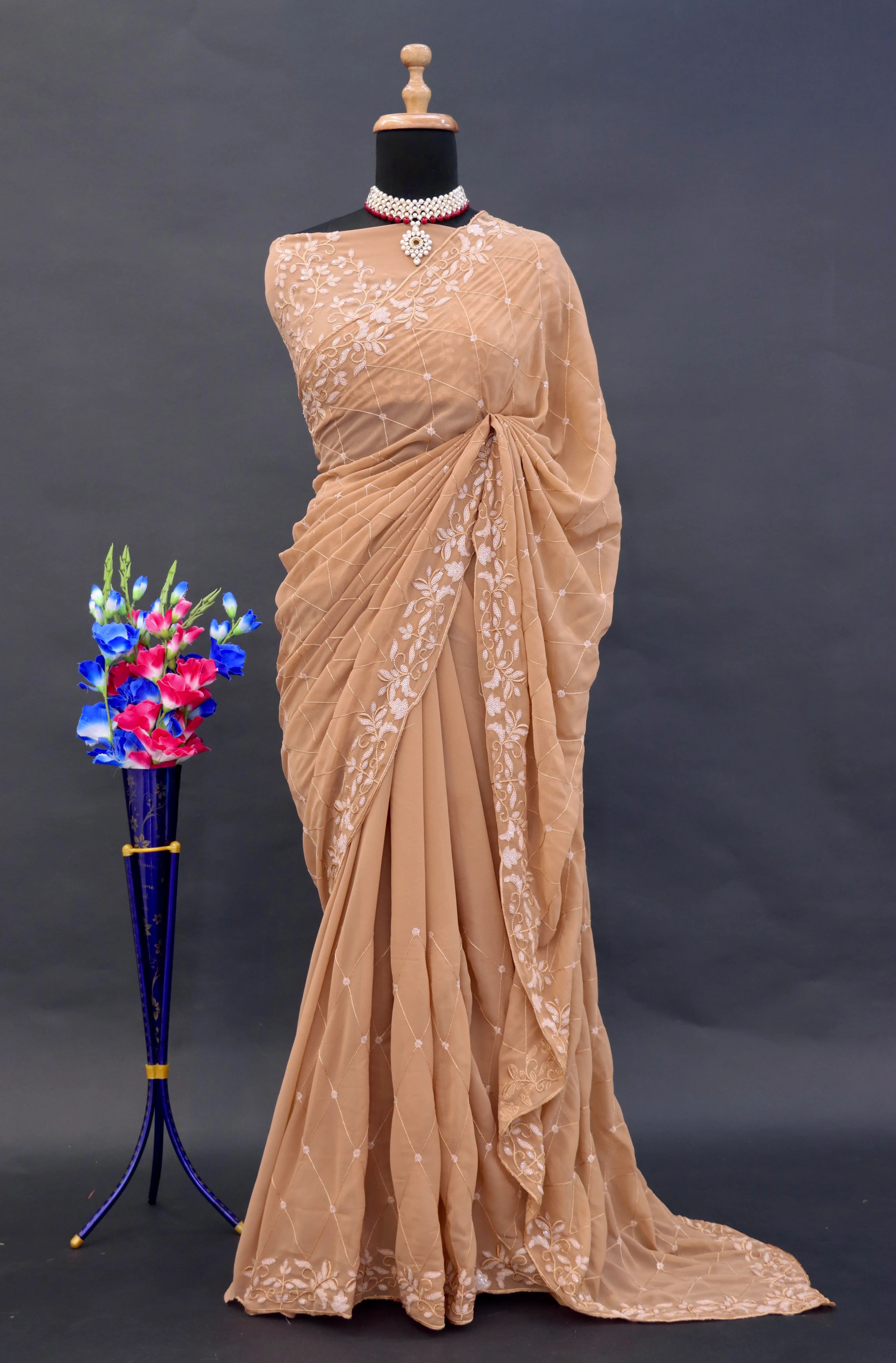 A captivating champagne georgette saree adorned with intricate hand embroidery, featuring exquisite