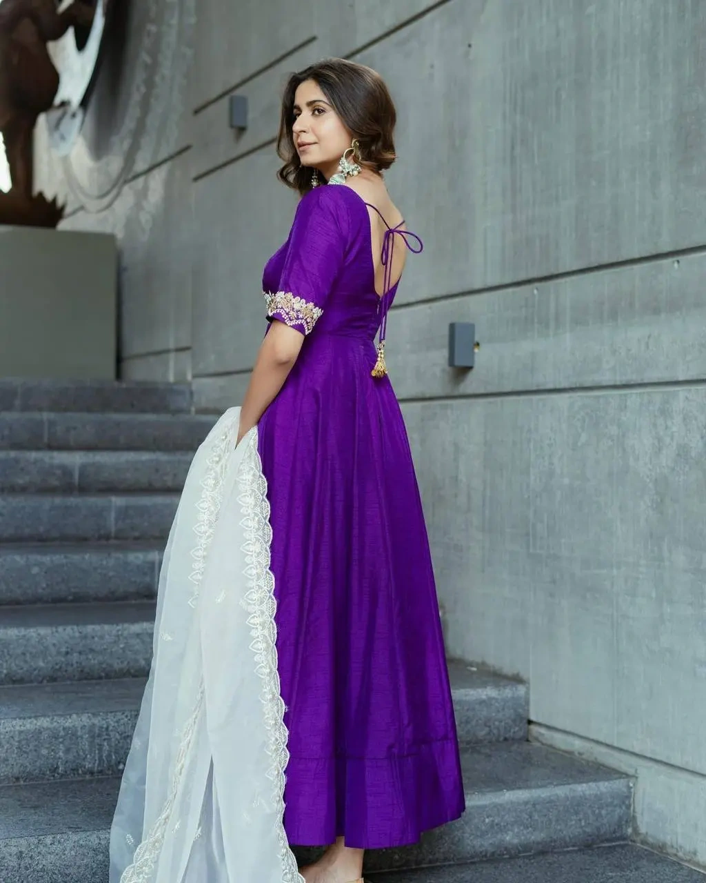 a woman in a purple dress standing in front of a building