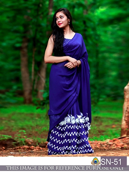 A woman in a blue Georgette saree and Banglori silk blouse stands gracefully among the trees in a se