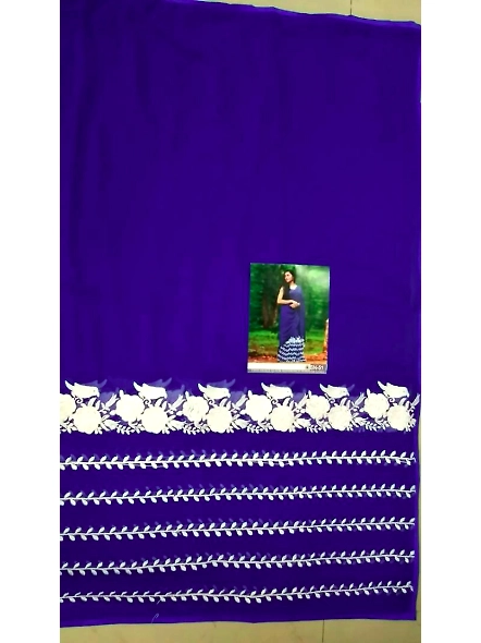 A beautiful woman wearing a blue Georgette saree and Banglori silk blouse poses elegantly in a lush 