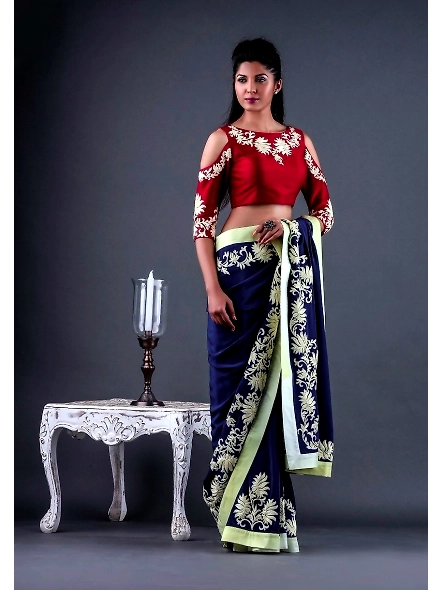 A woman elegantly dressed in a stylish red and blue sari, featuring a blue georgette fabric and a Ba