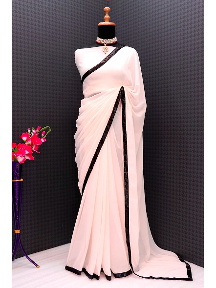 A woman elegantly dressed in a white sari with a black border, featuring intricate sequence work and