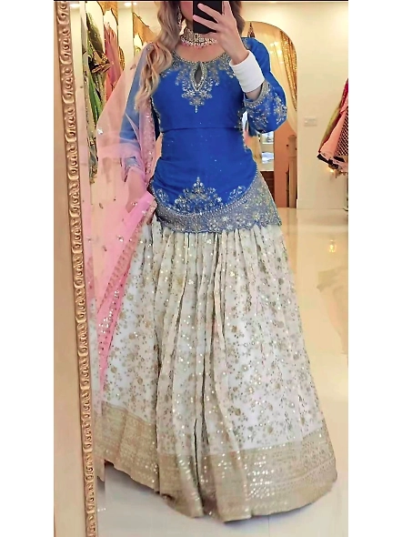 A woman dressed in a vibrant blue and pink lehenga, crafted from Chinon silk, ideal for celebratory 