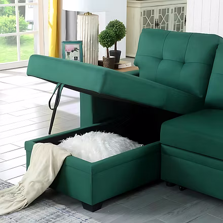 Upholstered green sofa cum bed with open hidden storage compartment, showing blanket and pillow — a 