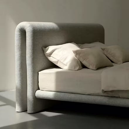 Studio close-up of Drift upholstered bed in neutral-beige fabric highlighting double-fold rounded he