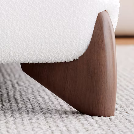 Close-up of the Ashlie bed’s walnut wood leg and white fabric upholstery, showcasing detailed crafts