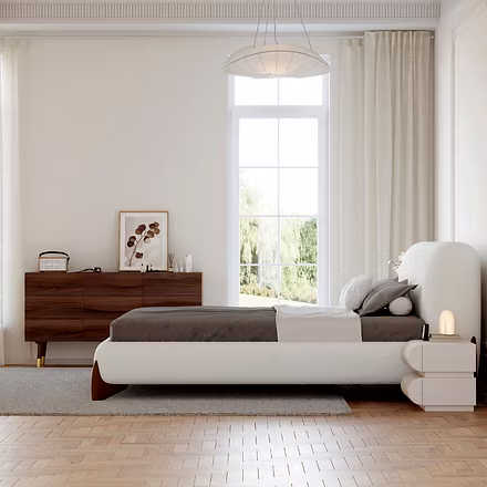 Bright bedroom with a white Ashlie upholstered bed and gray pillow, alongside a long wooden dresser