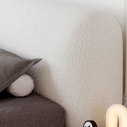 Bright bedroom with a white Ashlie upholstered bed and gray pillow, alongside a long wooden dresser