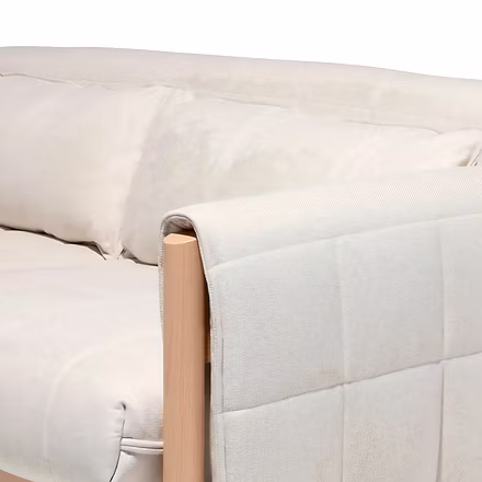(Armrest Corner): Wooden sofa armrest wrapped in quilted ivory fabric with teakwood frame detail.
