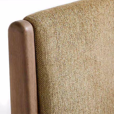 Close-up of textured beige upholstery and teak headboard edge showing fabric weave and wood grain — 