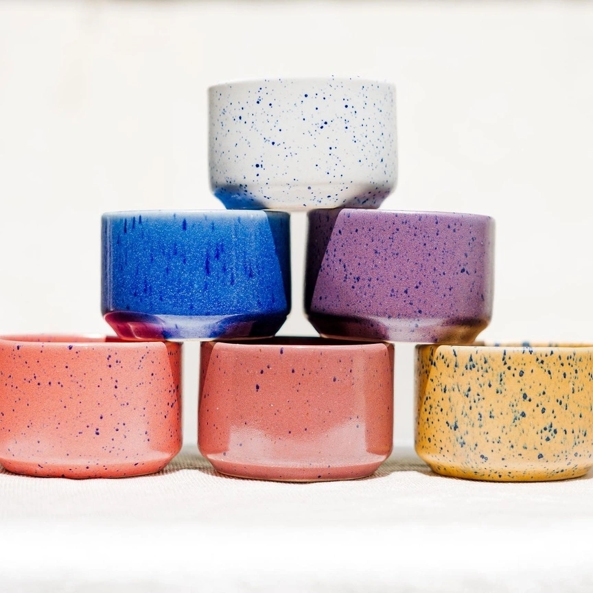 A pyramid of six colorful, speckled ceramic bowls against a white background.