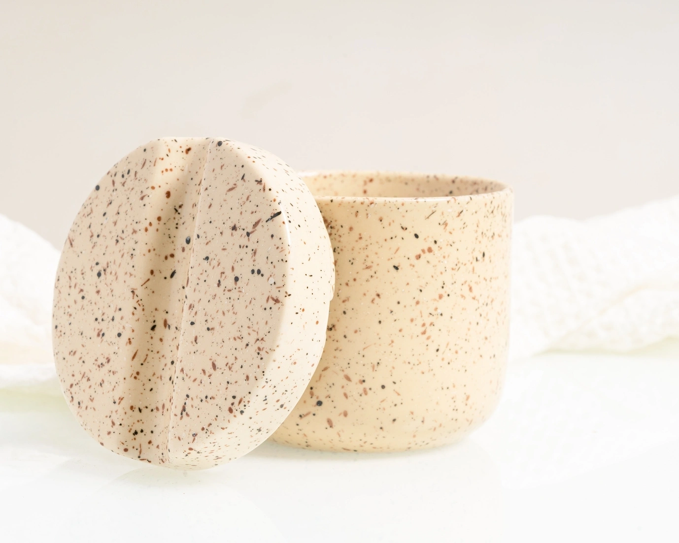 Speckled ceramic cup with matching saucer on a white background.