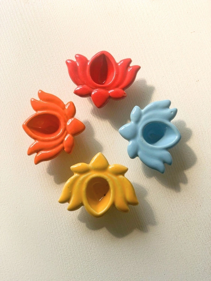 Four colorful, flower-shaped ceramic candle holders on a light background.