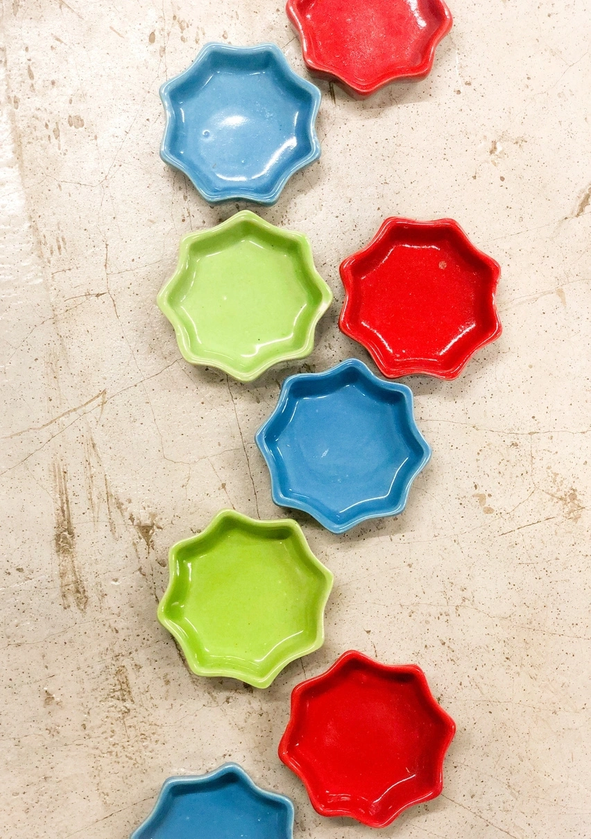 Alternating blue, green, and red star-shaped dishes arranged in a line on a speckled surface.