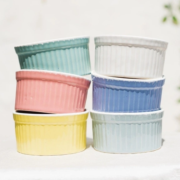 A stack of pastel-colored ceramic ramekins on a light background.