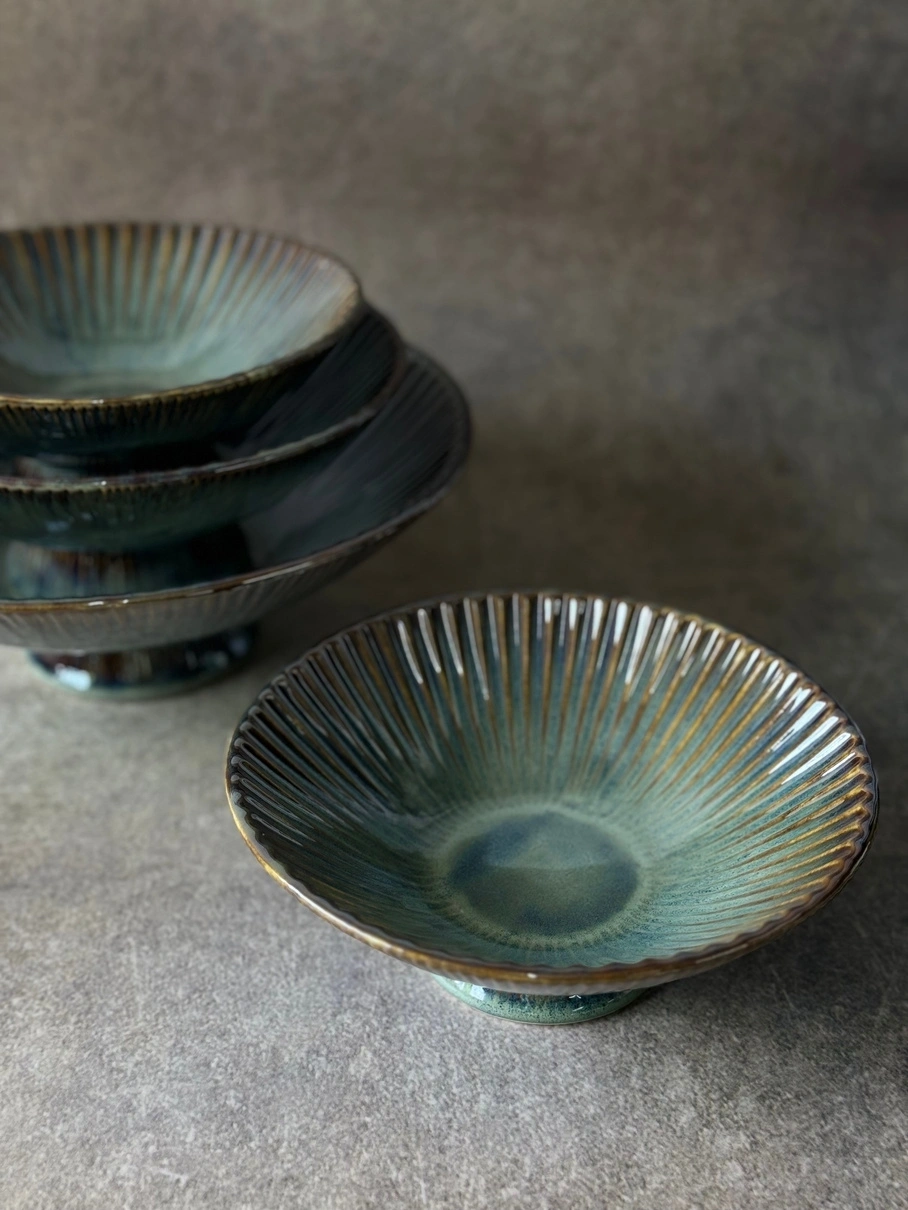 Stacked ceramic bowls with a textured blue-green glaze on a gray surface.