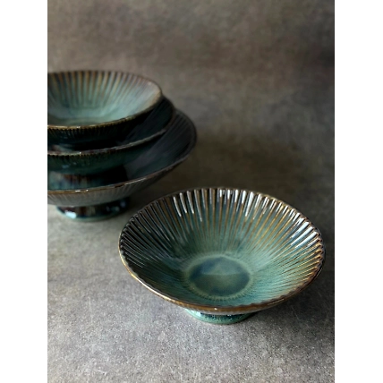 Stacked ceramic bowls with a textured blue-green glaze on a gray surface.