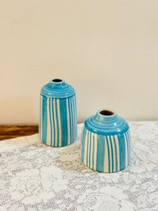 Two blue-striped ceramic vases on a lace tablecloth.